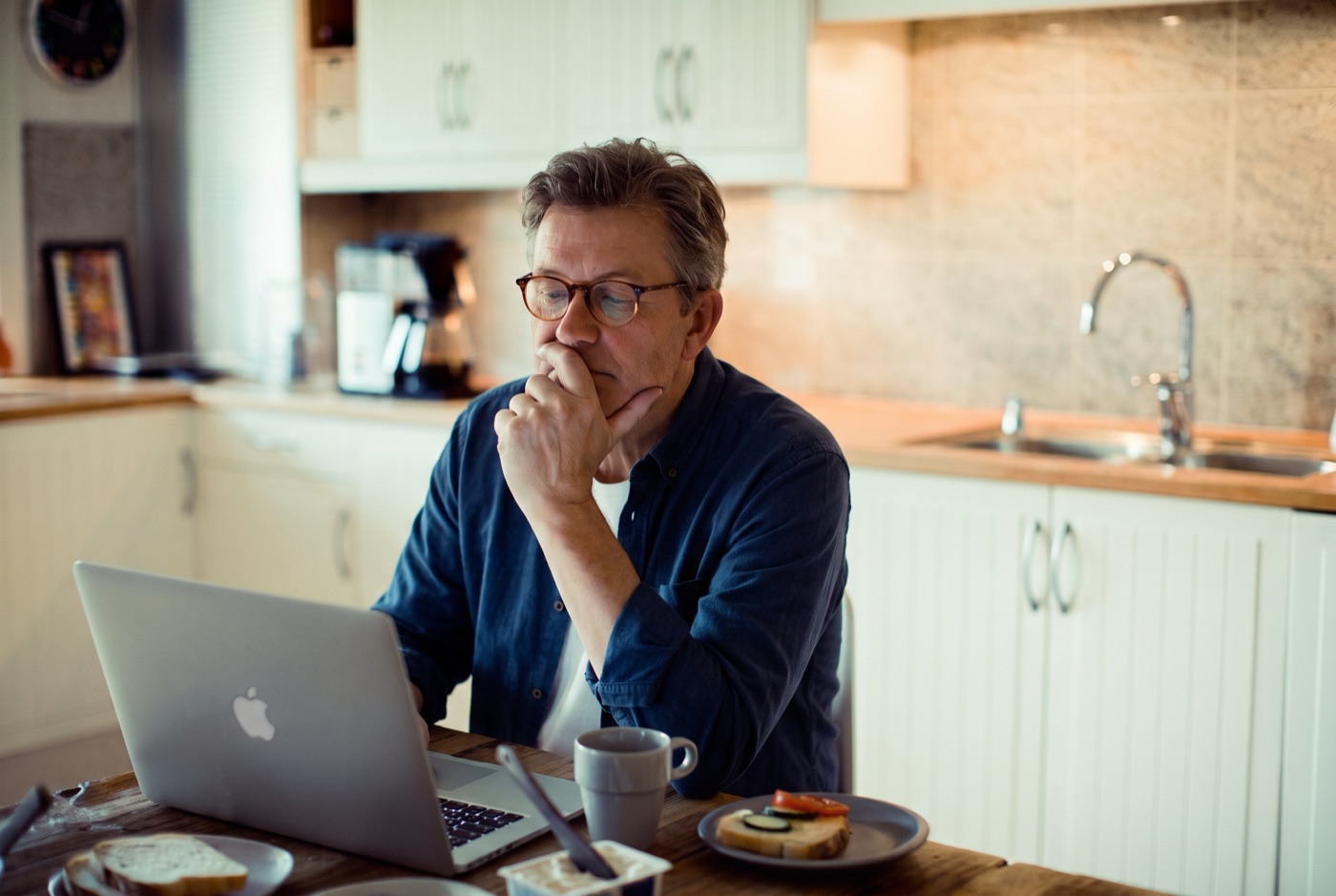 An editor considering a manuscript at his laptop