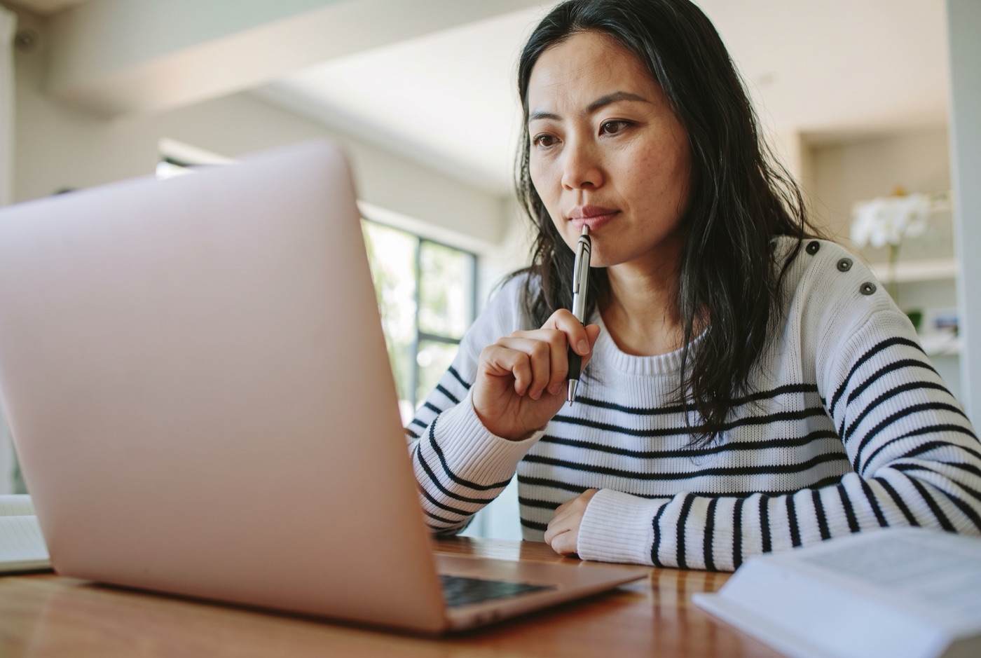 A reviewer reflecting on a manuscript beside her laptop